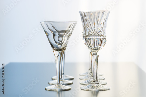 Decoration setup of wine and martini glasses set up in rows on a reflective table top.