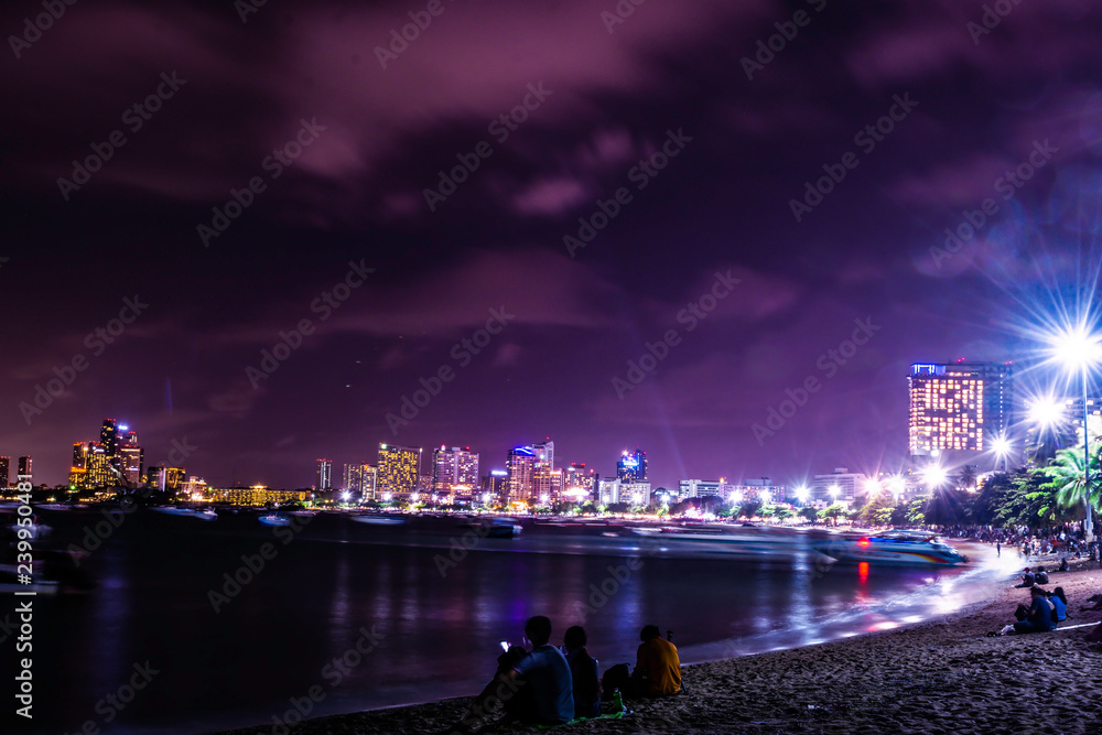 Beautiful night sky with skyscrapers in Jomtien beach Pattaya, Thailand, Crowd of people are relax on the beach in the night, Tourist are walking on the beach with cool wind air from sea