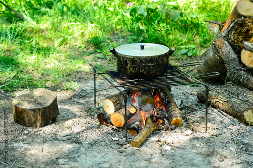 The pot on the barbecue camp grill is an open fire. Screensaver mobile kitchen. Background.