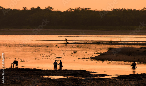 Asian women fishing in the river, silhouette at sunset