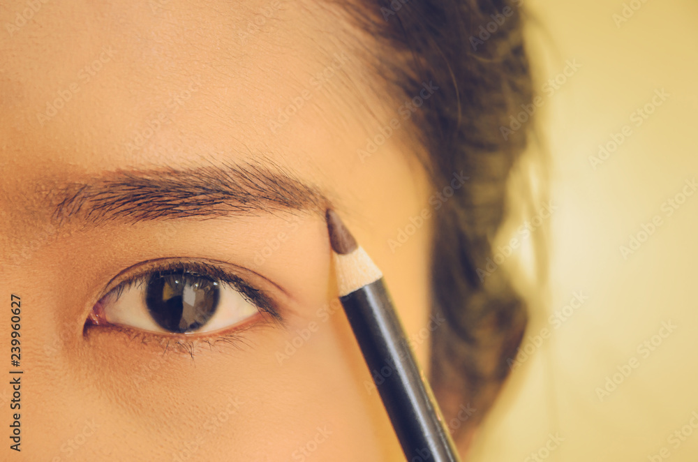 Naklejka premium Beauty face of Asian woman by applying eyebrow pencil and smooth skin by cosmetics.