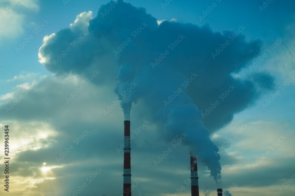 The smoke from the pipes of the power station closes the sky over the city. The sun is hidden behind clouds of smoke and steam