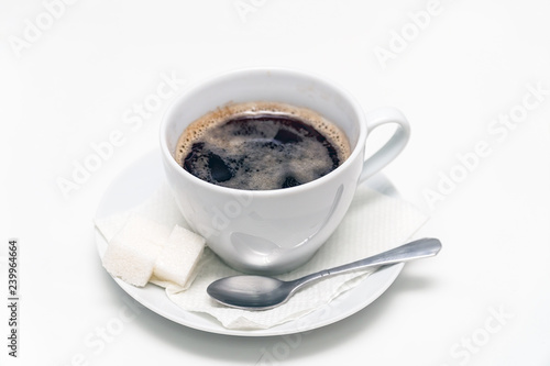 Cup of black coffee on a saucer with a napkin  a teaspoon and lumps of sugar