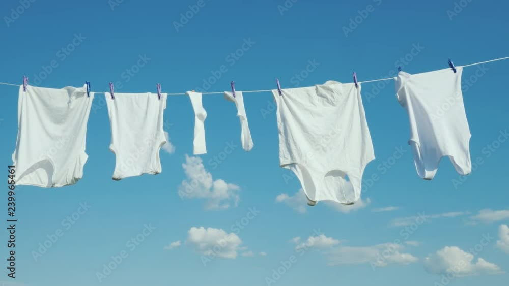 White linen dries on a rope against a clean blue sky White linen dries on a rope against a clean blue sky