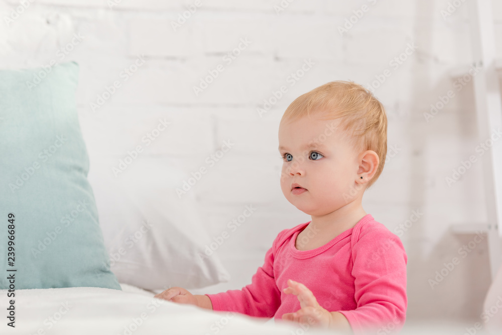 adorable kid leaning on bed and looking away in children room adorable kid leaning on bed and looking away in children room