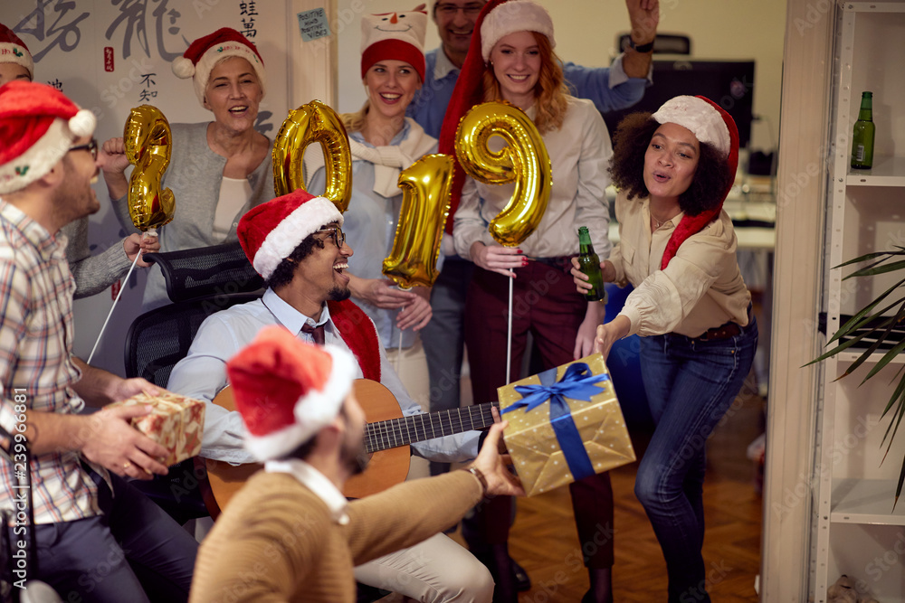 Obraz premium Happy business people have fun and dancing in Santa hat at Xmas party.