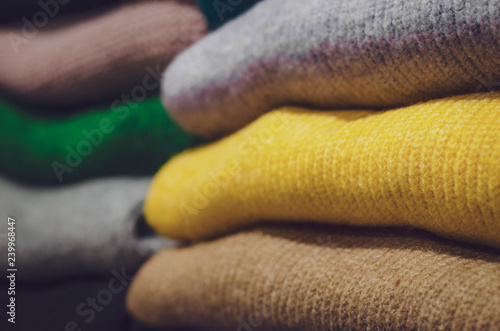 folded clothes in the store  colored sweatshirts and sweaters folded up on the shelves of the store  backgrounds for the text or advertisements of women s clothing store or showroom