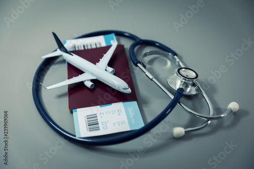 travel insurance - passport with flight ticket and stethoscope on gray background