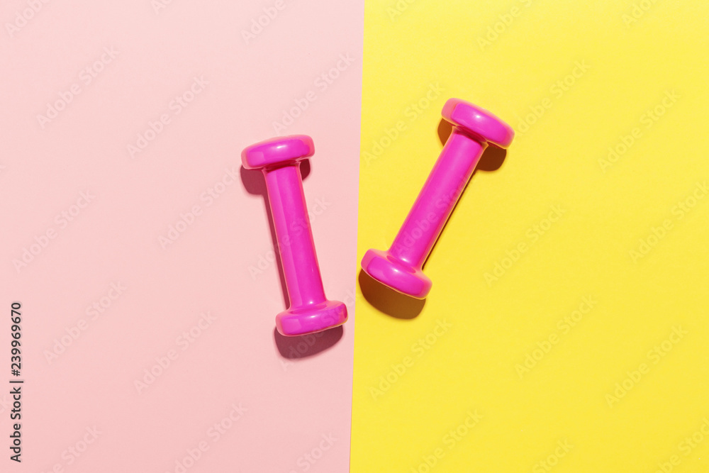 Dumbbells flat lay on pink and yellow Dumbbells flat lay on pink and yellow