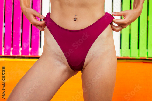 hip , waist navel piercing of young fitness model in red underpants closeup colorful background.hairy bikini area woman epilation, lacer hair removal depilation summer season on the beach shugaring