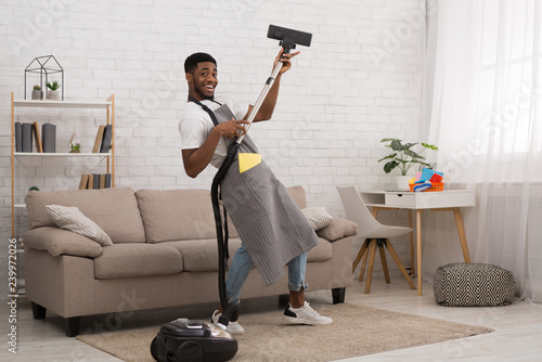 Young man cleaning house with vacuum cleaner