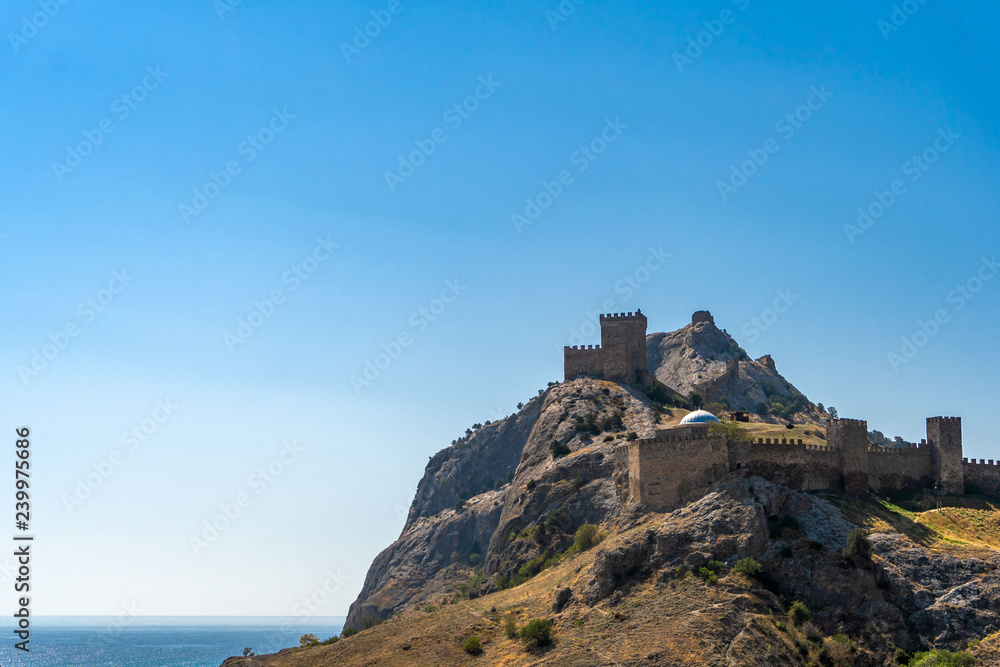 View of the Genoese fortress in the city of Sudak, Crimea, against a blue sky.