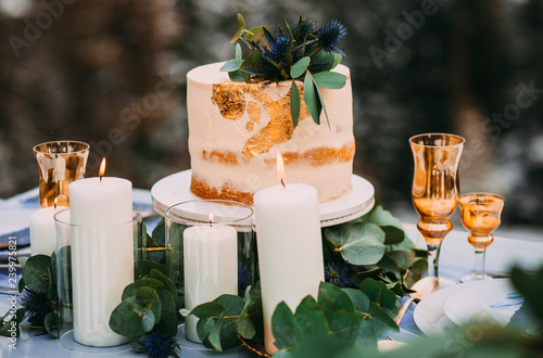 Amazing beige cake decorated with flowers, standing on the table near to candles