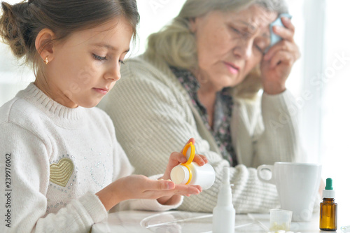 Girl giving medicine to sick senior woman