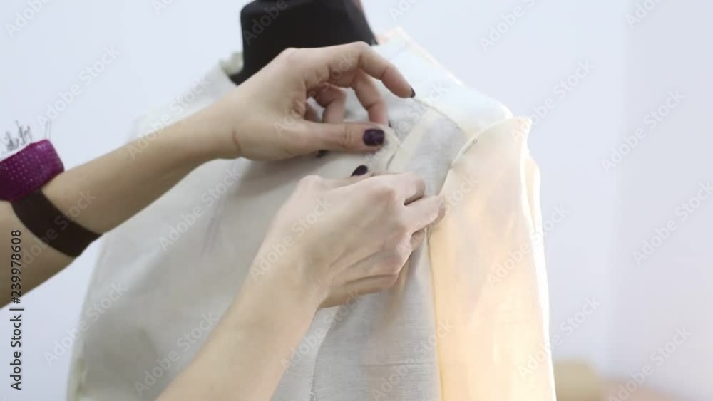 Dressmaker pins up a jacket in the initial stage of tailoring using sewing pins in a sewing workshop Dressmaker pins up a jacket in the initial stage of tailoring using sewing pins in a sewing workshop
