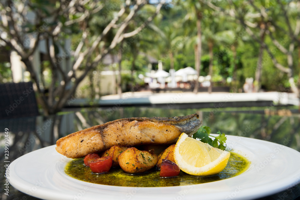 Deep Fried Salmon Seabass fish cut meat with fried potato chip, Fusion food stylish arrange on glass table along ocean mangrove tree Island, empty copy space for text logo Yummy