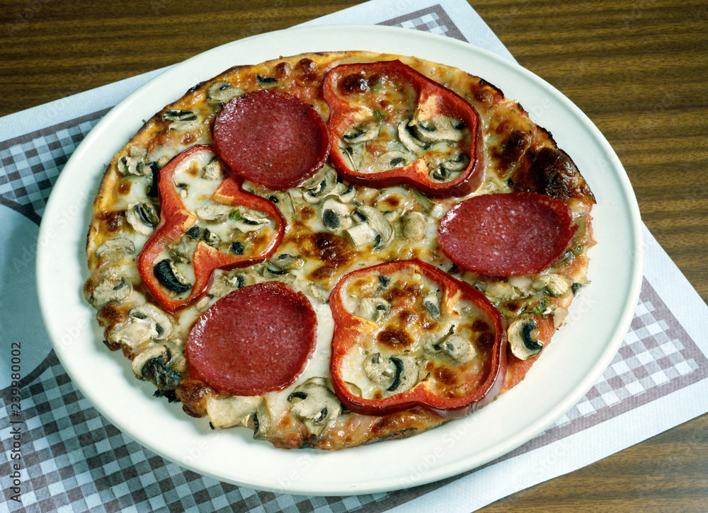 Una pizza con tomate, queso, salami,  pimientos y chamiñones. 