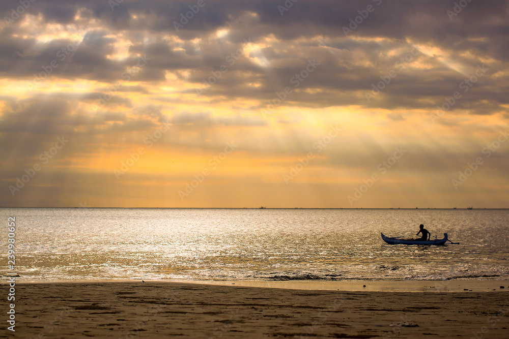 Sunset with sea view and lonely boat in Bali, Indonesia