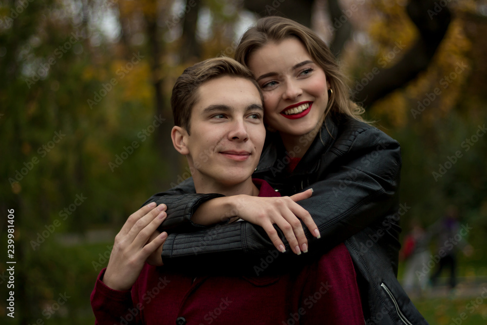 smiling girl hugging a guy from behind the neck, couple in love, date, love story