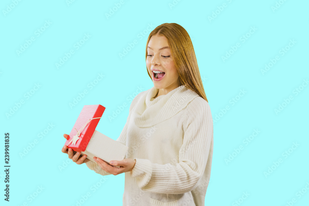 Lovable young woman in white sneakers posing with present box. Studio portrait of fascinating girl making kissing face expressing while holding big gift