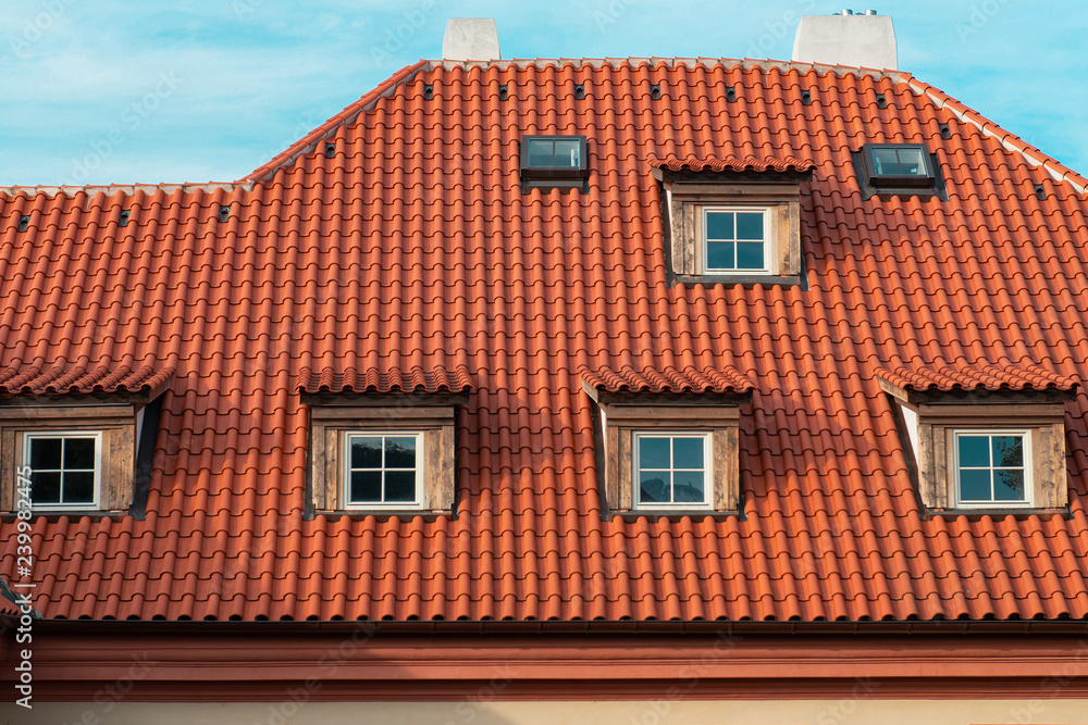 Beautiful old house with orange roof with multiple windows and  blue sky. Part of old town in Prague.