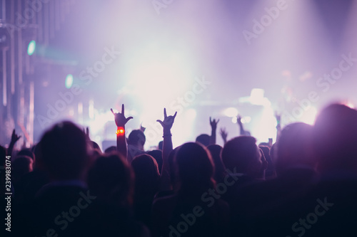 Concert, event or party concept. People with hands up at the scene, spotlight, colored light.