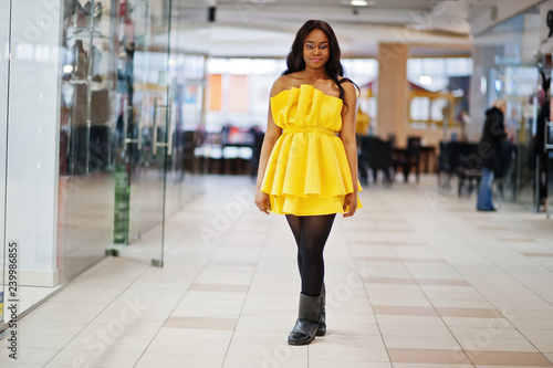 Stylish african american woman at yellow dreess posed at mall.