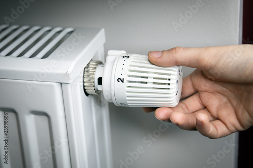 hand adjusting temperature on radiator. energy saving concept