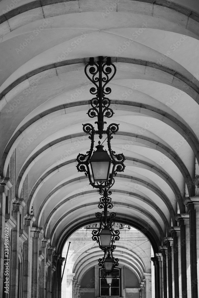 Lanterns and arches at Commerce square (Praca do Comercio) in Lisbon, Portugal. Black and white photo.