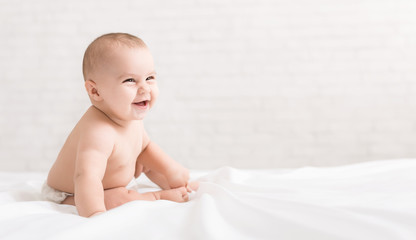 Beautiful laughing baby sitting on white background