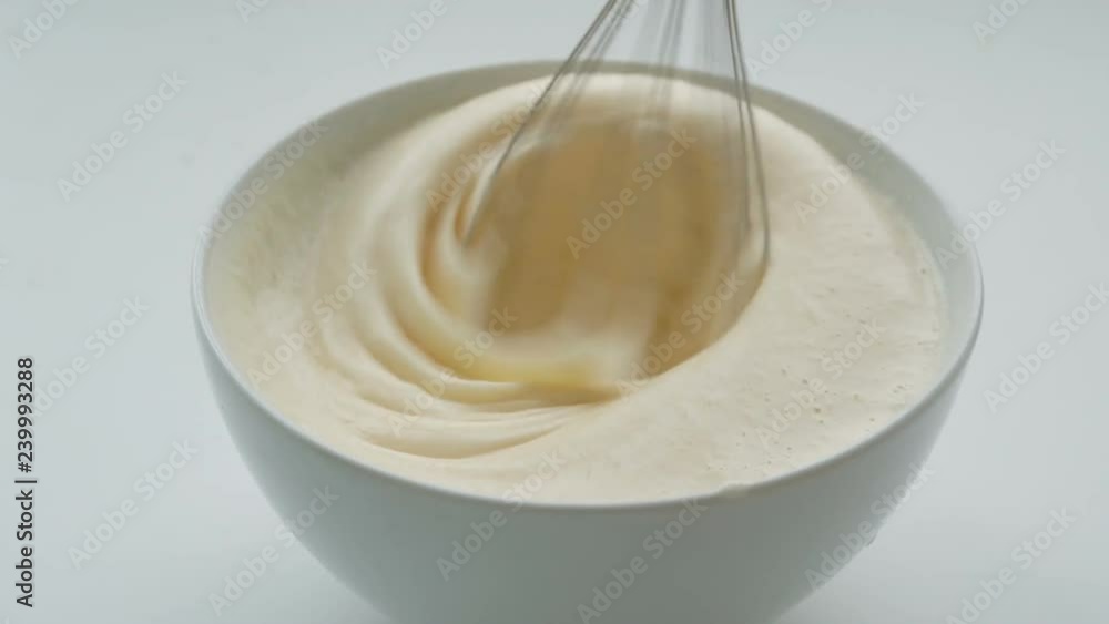 Whisk whipped egg whites and sugar in white bowl Whisk whipped egg whites and sugar in white bowl