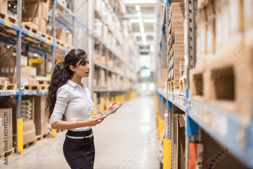 Young woman with black hair holding digital tablet in warehouse photo