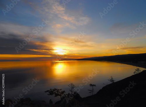 Bay in golden shades at sunset. Bright sunrise landscape in sea. Flaming colors of early morning. Dawn silence on lake.
