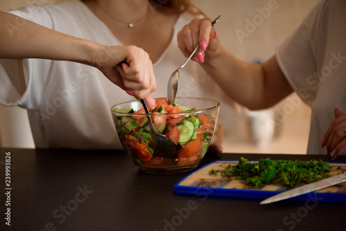 Young sisters making vegetable salad at home