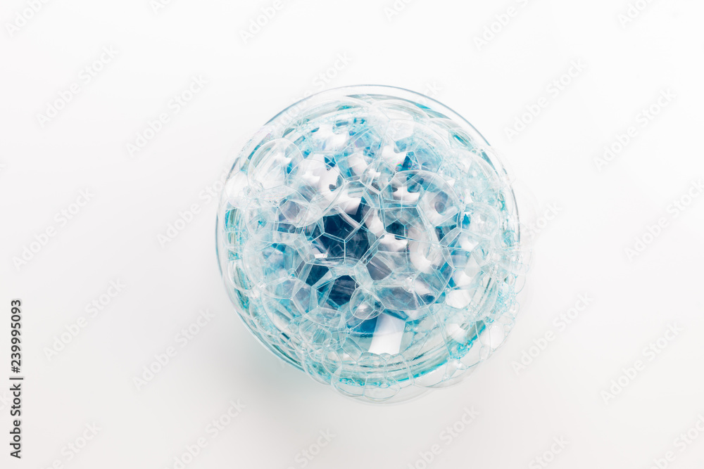 A circle of soap bubbles from blue shower gel on a white background. A circle of soap bubbles from blue shower gel on a white background.