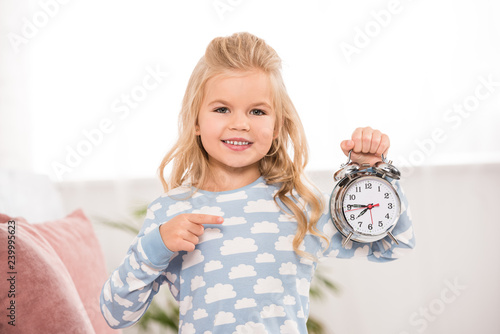 smiling cute child pointing with finger at clock