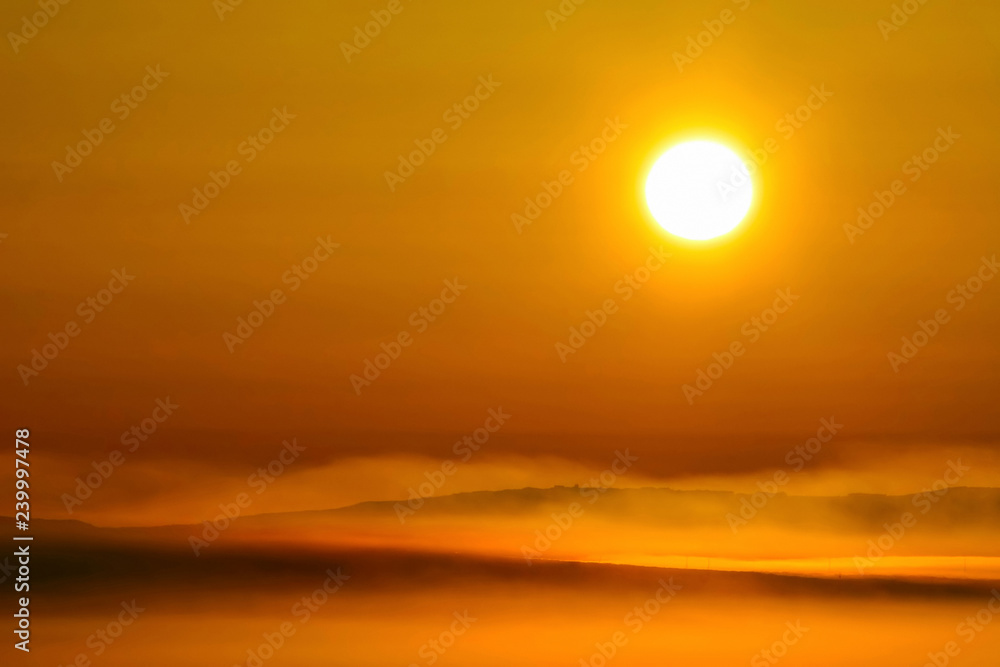Beautiful sunrise over the tundra. Early morning in May. Over the Anadyr estuary clubs of fog rise. The large disk of the sun colors the atmosphere in golden color. Chukotka, the Far East of Russia.