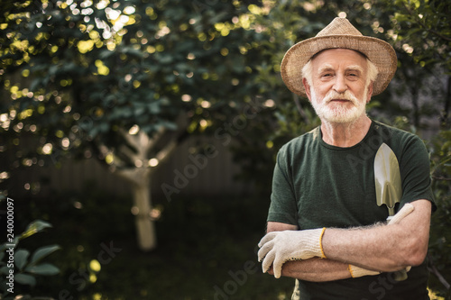 Old gardener standing in garden after work photo