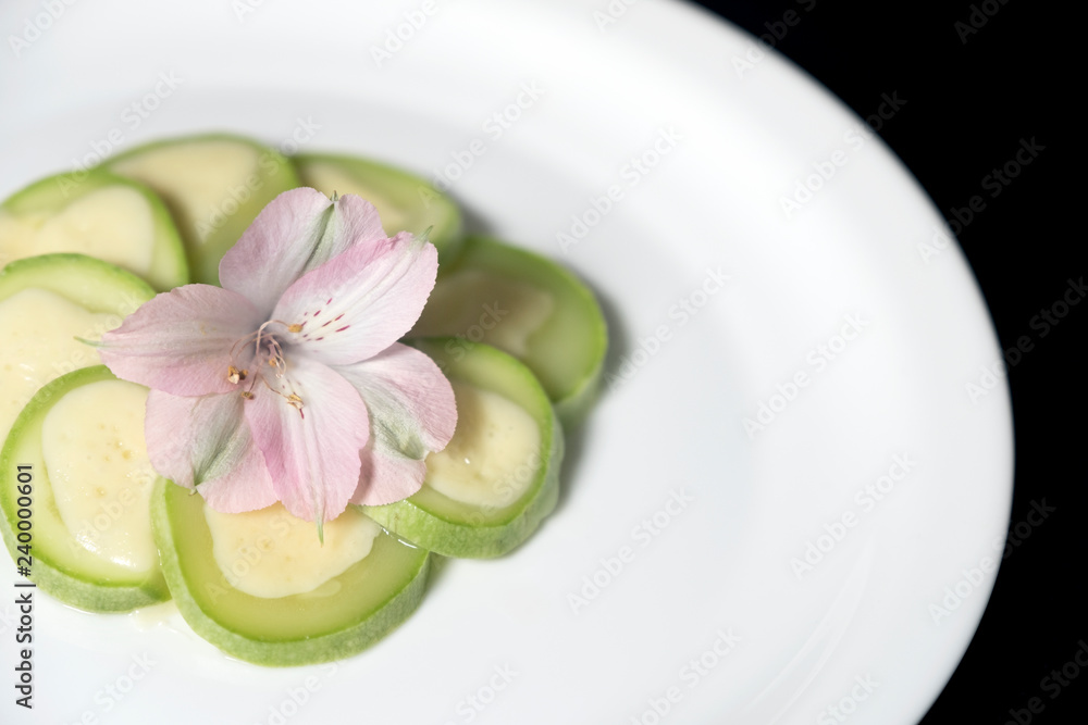 Courgettes with cheese on a white plate, decorated with a flower. Courgettes with cheese on a white plate, decorated with a flower.