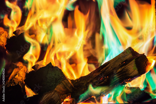 multi-colored flame of fire burns in the fireplace with firewood