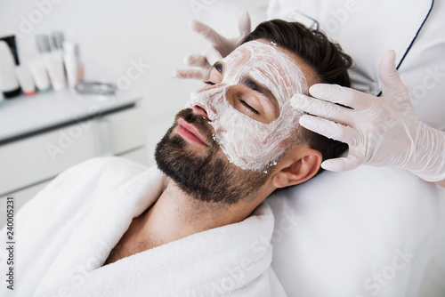 Принти на полотні Hands in rubber gloves touching temples of relaxed man in salon