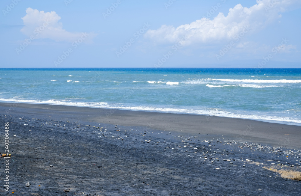 Oceanic coast with black volcanic sand on the island of Bali
