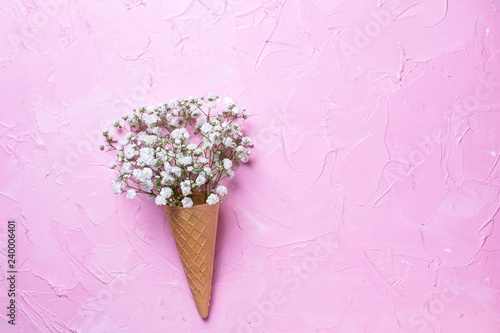 Fresh white gypsofila  flowers in waffle cone on  pink textured background.