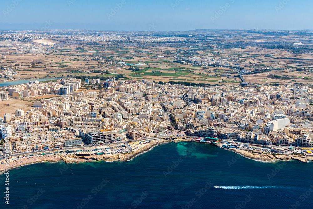 Aerial view of Bugibba town, St. Paul's Bay in the Northern Region, Malta. Popular tourist resort destination with promenade, hotels, restaurants, pubs, clubs, and a casino.