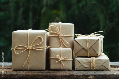 Stack of simple eco friendly gift box package wrap with brown paper in old wooden table background, green present concept