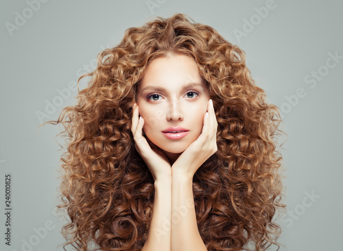 Perfect female face. Attractive girl with long curly hair. Haircare and cosmetology concept