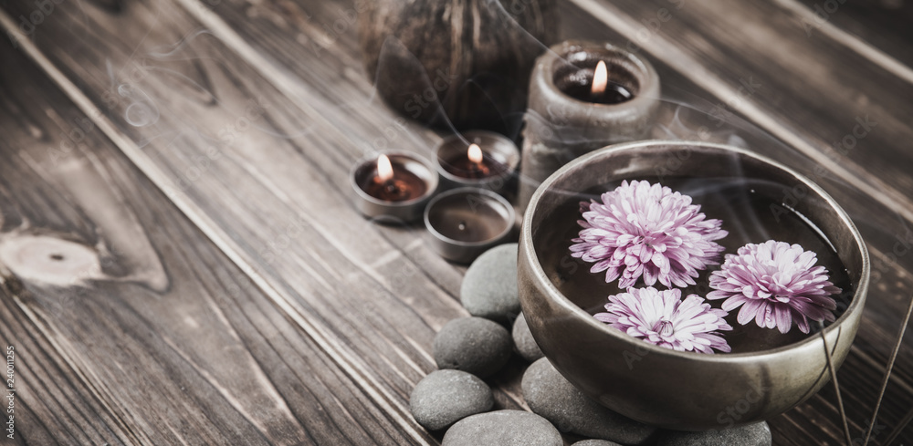 Singing bowl with candles with pebbles on dark wooden background