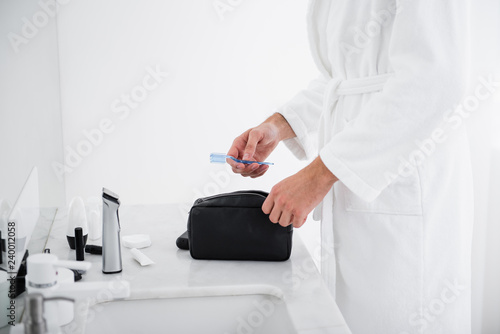Close up of person putting toothbrush into the toiletry bag