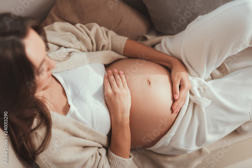 Photo Careless lady lying and holding her hands on pregnant belly
