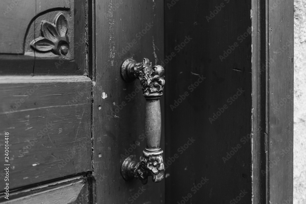 Obraz premium Beautiful old wooden door with handle in ancient city of Antalya city, Turkey. Horizontal black and white color photography.